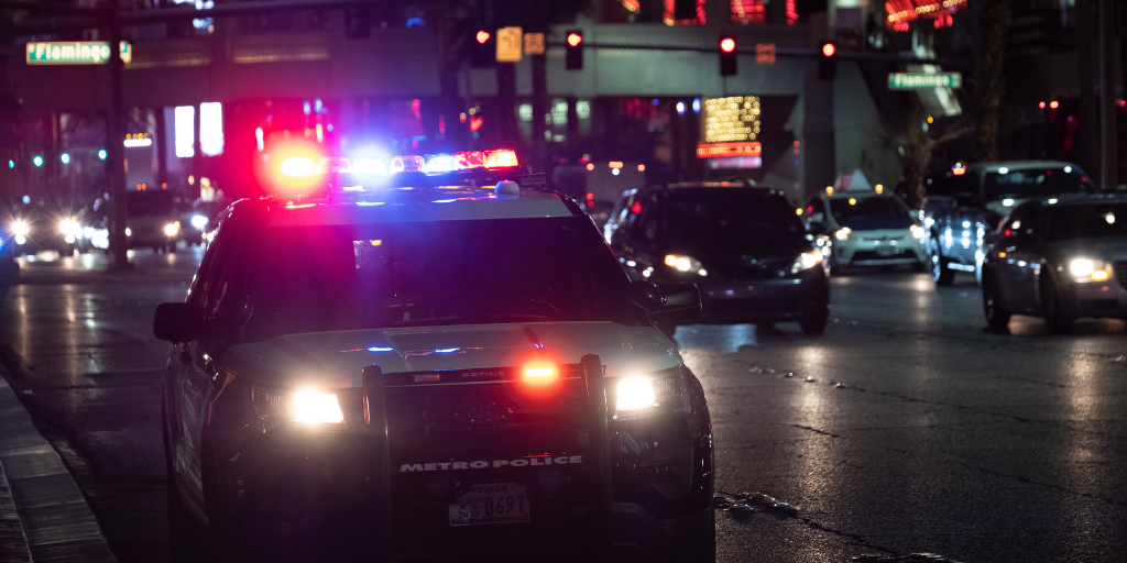 Police car with headlights flashing on busy street at night